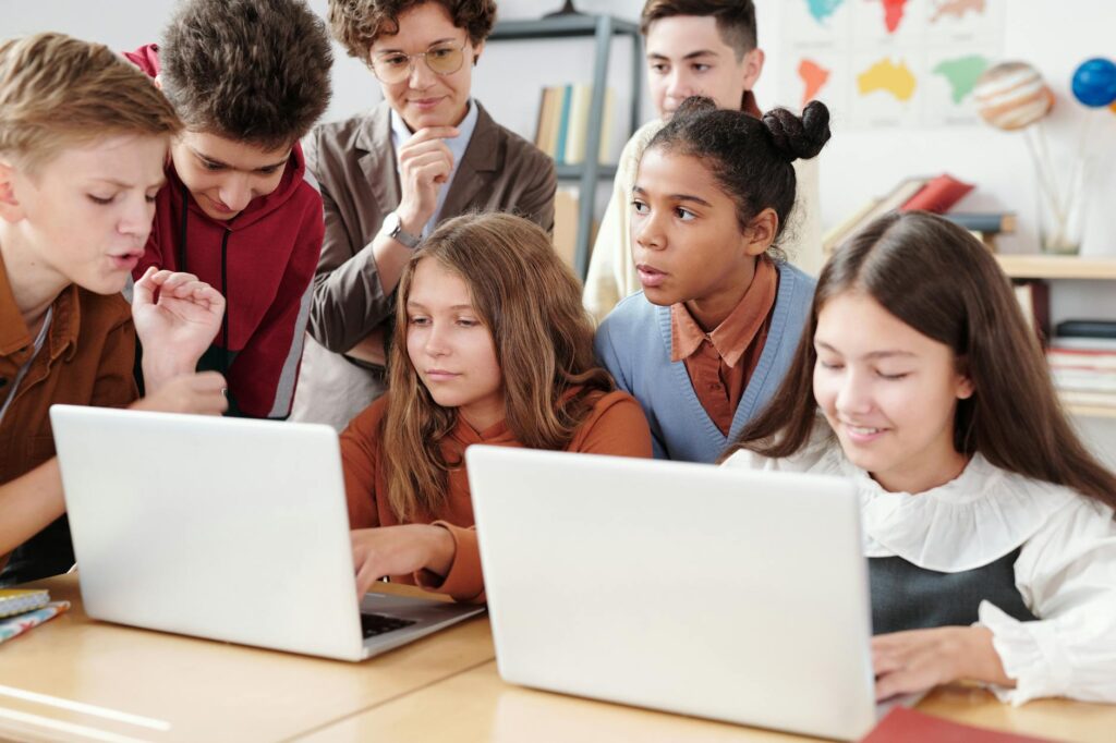 a two girls using laptop with classmates