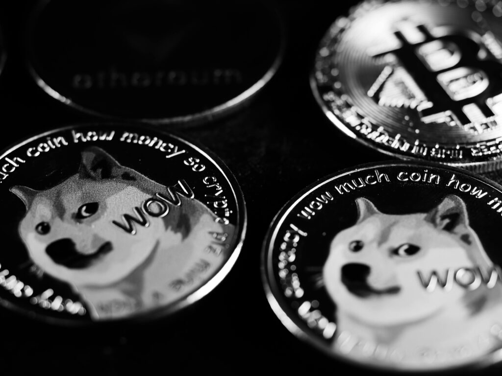 Monochrome image focusing on physical Dogecoin and Bitcoin coins, highlighting cryptocurrency.